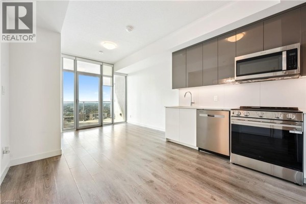 Open concept kitchen with stainless steel appliances, white cabinets, grey upper cabinets, and a sink. - 60 Frederick Street Unit# 2913, Kitchener