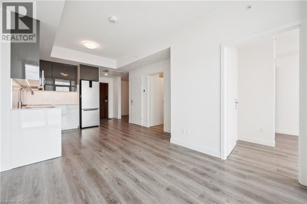 View of the kitchen area, dining space, and hallway leading to a bedroom and another door. - 60 Frederick Street Unit# 2913, Kitchener