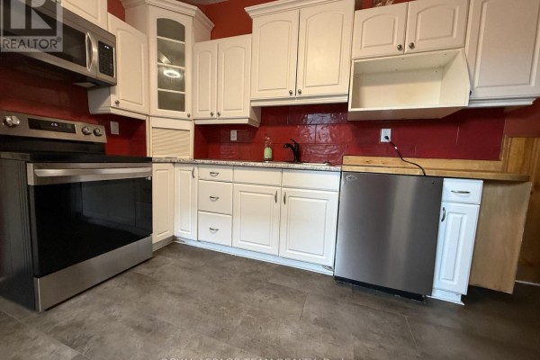 Kitchen with white cabinets, stainless steel stove, dishwasher, and red tile backsplash. - 60 Herridge Street, Ottawa