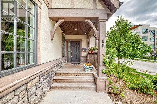 Front porch with wooden steps, columns, and a dark front door at 60 Hong Kong Road. - 60 Hong Kong Road Sw, Calgary