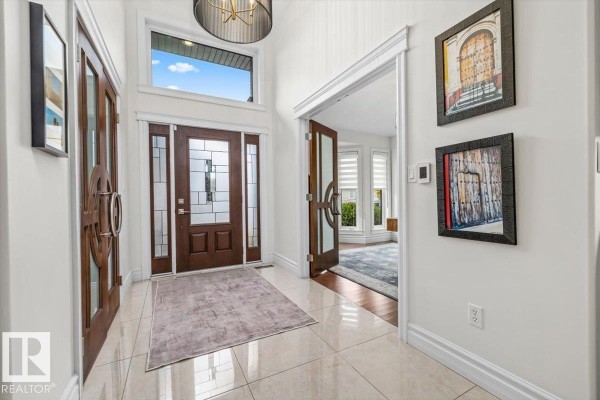 Spacious entryway of a luxury home featuring a dark wood front door with glass inserts and tile flooring. - 60 Lafleur Dr, St  Albert