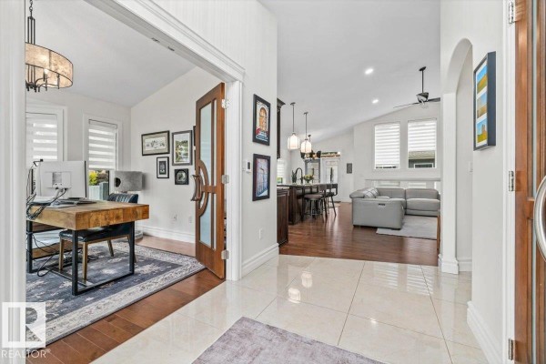 View from the entryway into an office and open-concept living area with hardwood floors and white walls. - 60 Lafleur Dr, St  Albert
