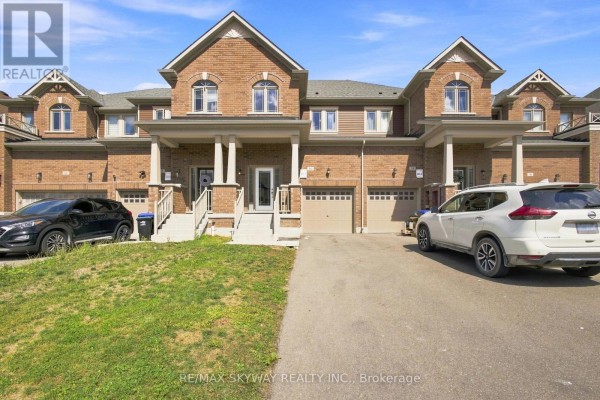 Street view of brick townhouses with garages and front yards, featuring parked cars and RV. - 60 Lorne Thomas Place, New Tecumseth