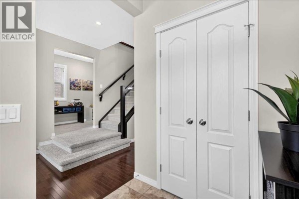 Interior view of a home's entryway with a staircase, dark hardwood floors, and a closet with double doors. - 60 Mahogany Grove Se, Calgary