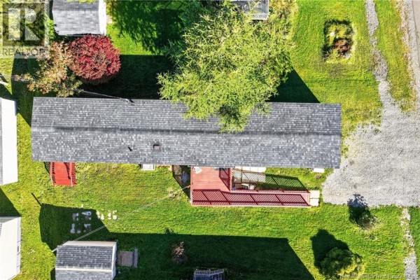 Top-down view of the beige mobile home with a grey asphalt shingle roof, surrounded by green lawn and trees. - 60 Midway, Moncton