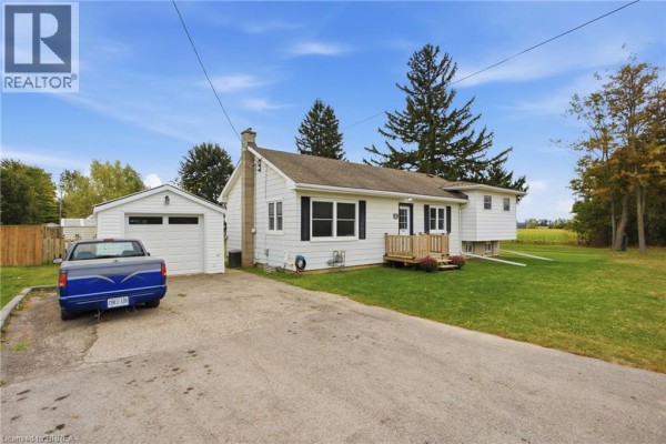 Front and side view of the bungalow with a driveway and detached garage. - 60 Railway Street W, Princeton