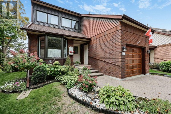 Close-up view of the front entrance and garage of the brick house with a landscaped garden. - 60 Riverview Road, New Tecumseth