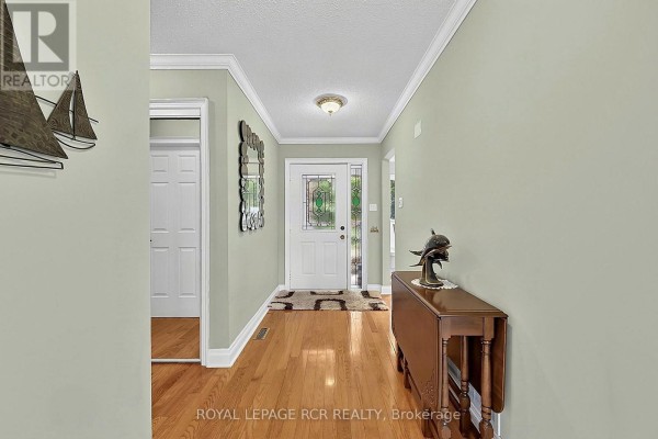 Interior entryway with light green walls, hardwood floors, a console table, a mirror, and a front door. - 60 Riverview Road, New Tecumseth