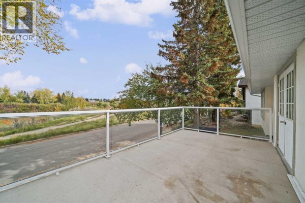 Concrete deck with glass railing overlooking a green space and trees. - 60 Silverview Way Nw, Calgary