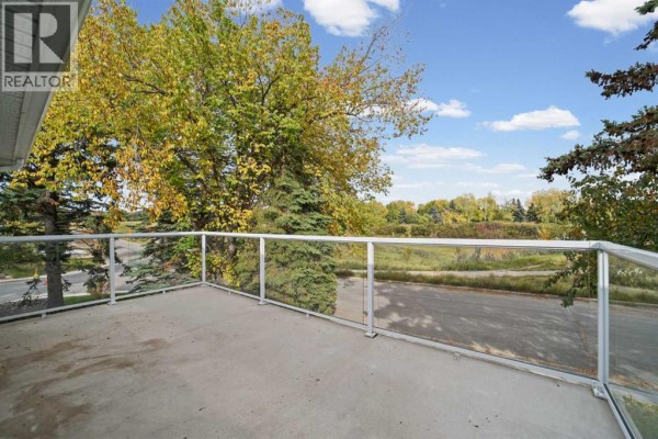 View from deck showing trees and a paved pathway below. - 60 Silverview Way Nw, Calgary