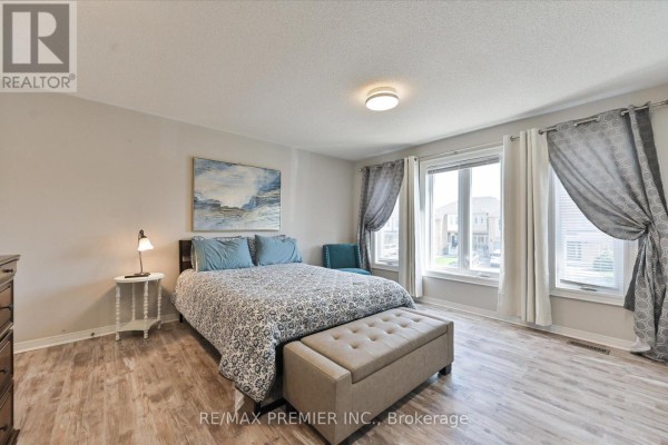 Bedroom with a king-size bed, patterned bedding, light wood floors, and large windows. - 60 Tumbleweed Court, Vaughan