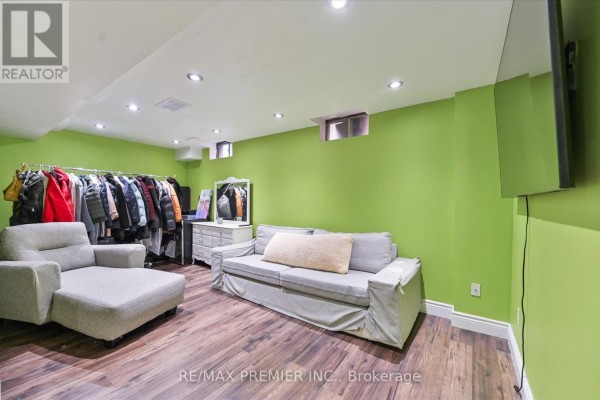 Finished basement room with lime green walls, a sofa, chaise lounge, and clothing rack. - 60 Tumbleweed Court, Vaughan