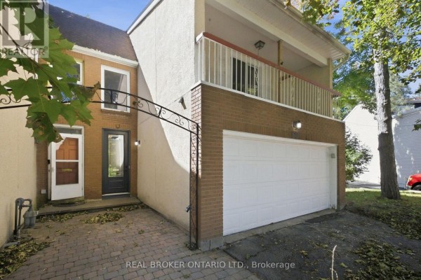 Close-up of the townhouse entrance, brick facade, and double garage door. - 60 Tybalt Crescent, Ottawa