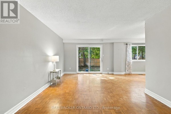 Living room with parquet flooring, a lamp on a side table, and a sliding glass door. - 60 Tybalt Crescent, Ottawa
