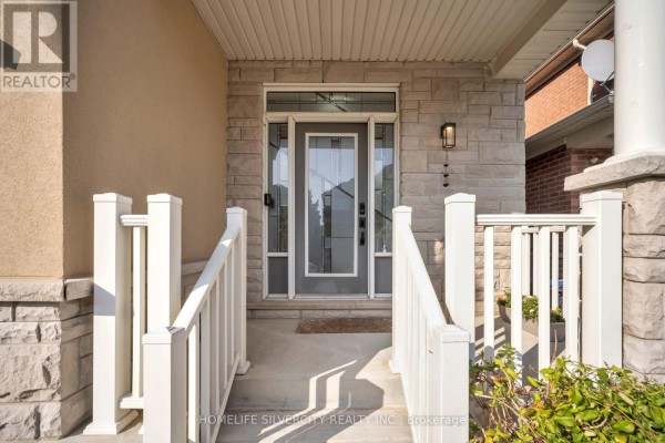 Front entrance of a house with a glass door, stone accents, and white railings. - 60 Tysonville Circle, Brampton
