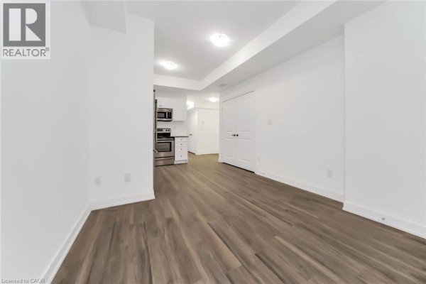 Interior view of a living area with white walls, wood-look floors, and a kitchen. - 60 Winston Park Boulevard Unit# 60, Toronto