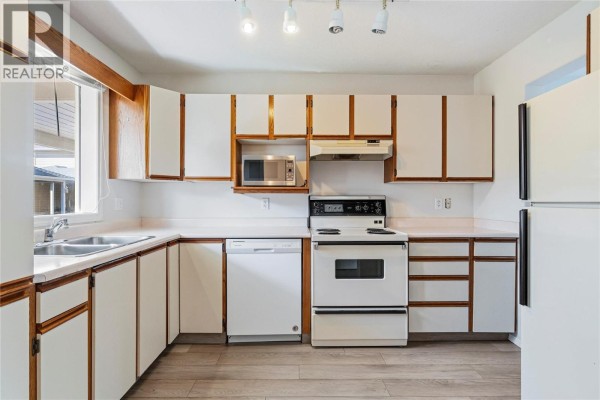Kitchen with white cabinets, white countertops, and stainless steel appliances. - 600 10 Street Sw Unit# 6, Salmon Arm