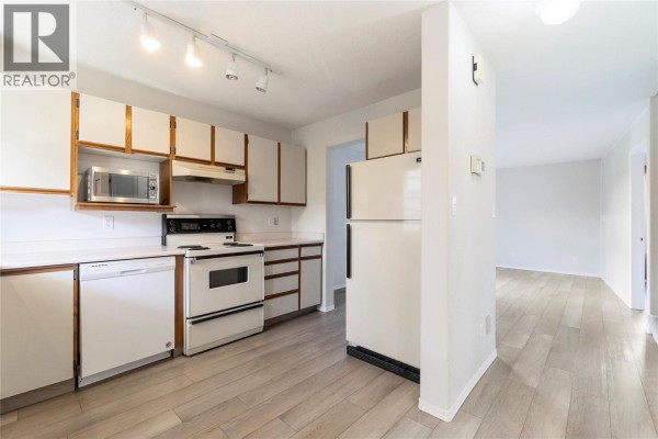 View of the kitchen and adjacent dining area with light wood floors. - 600 10 Street Sw Unit# 6, Salmon Arm