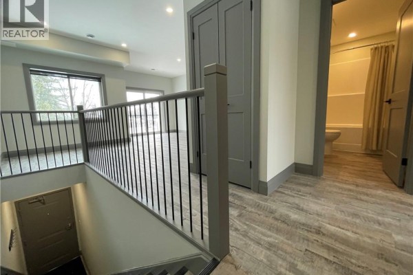 Interior view of a staircase leading down, with a hallway and doorway to a bathroom. - 600 Norfolk Street Unit# 303, Simcoe