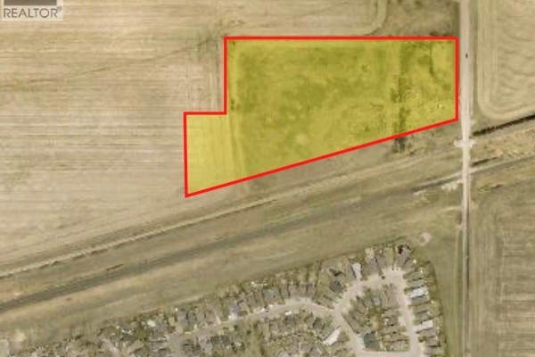 Aerial view of the property outlined in red, showing fields and the road. - 600 Prince Of Wales Drive, Regina