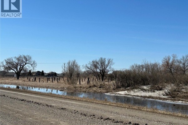 View of bare trees and a partially frozen ditch along a rural road on a sunny day. - 600 Prince Of Wales Drive, Regina