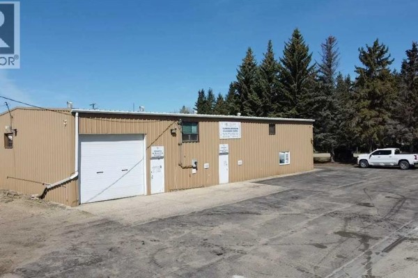 Tan-colored industrial building with a large white roll-up door, two personnel doors, and asphalt lot. - 6001 40 Avenue, Wetaskiwin