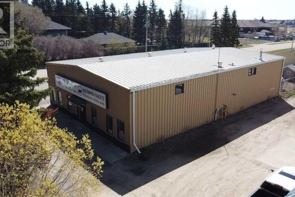Aerial view of industrial buildings and hangars with open fields and a road in the distance. - 6001 40 Avenue, Wetaskiwin
