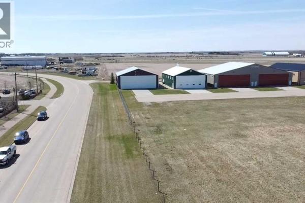 Side view of a tan building with three white roll-up doors numbered 2, 3, and 4. - 6001 40 Avenue, Wetaskiwin
