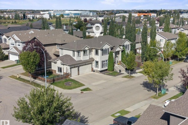 Wide exterior shot of a beige two-story house with a double garage and a paved driveway in winter. - 6002 46 Av, Beaumont