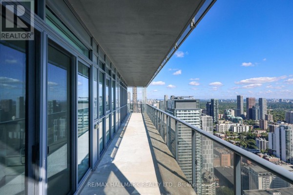 View from a balcony looking down the length of the balcony and the city skyline beyond. - 6005 - 7 Grenville Street, Toronto