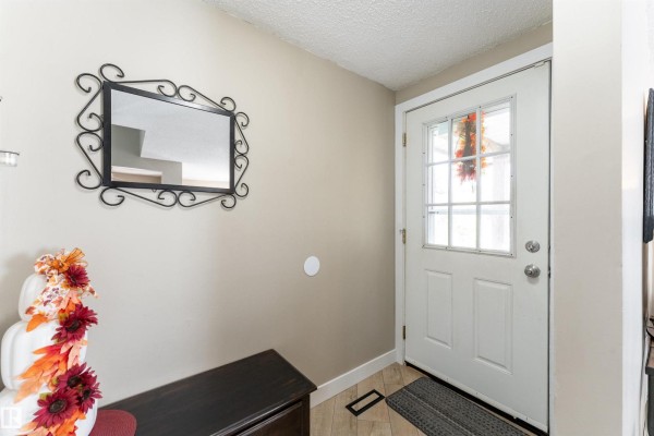 Entranceway with beige walls, a white door with glass panes, and a decorative mirror on the wall. - 6007 37 Av Nw, Edmonton