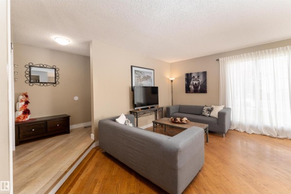 Living room with two gray sofas, a coffee table, a television, and hardwood floors. - 6007 37 Av Nw, Edmonton