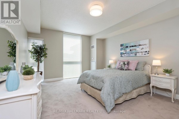 Bedroom with a king-size bed, beige carpet, a dresser, and a large window with blinds. - 601 - 1 Hurontario Street, Mississauga