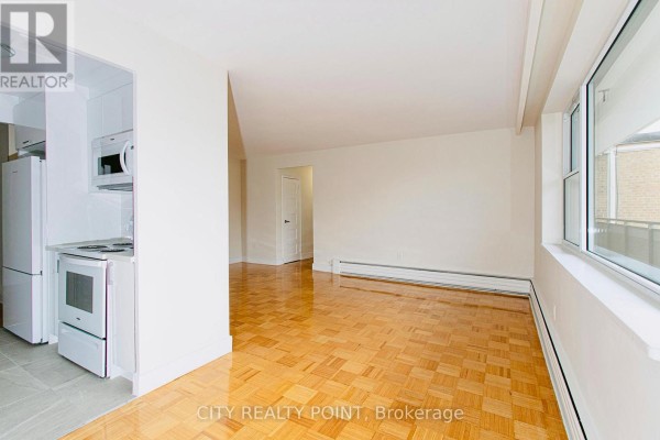 Open-concept living space with parquet floors and a large window overlooking the city. - 601 - 2 Grandstand Place, Toronto