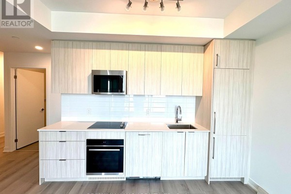 Kitchen with light wood cabinets, white tile backsplash, stainless steel appliances, and quartz countertops. - 601 - 20 Deans Drive, Toronto