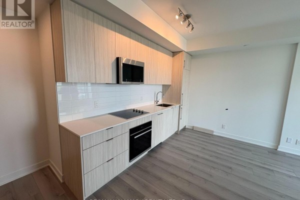 Modern kitchen with light wood cabinetry, white tile backsplash, stainless steel appliances, and quartz countertops. - 601 - 20 Deans Drive, Toronto
