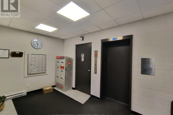 Apartment entryway with tiled floor, beige walls, wood accents, and kitchen visible. - 601 - 222 Guigues Avenue, Ottawa