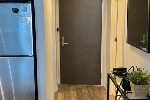 Apartment entryway with stainless steel refrigerator, dark door, and laminate flooring. - 601 - 411 Mackay Street, Ottawa