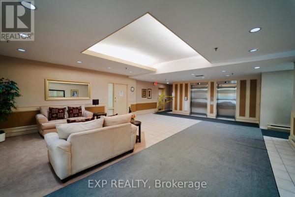 Interior view of an apartment entryway with white walls, a closet with mirrored doors, and a light wood door. - 601 - 432 Main Street E, Hamilton