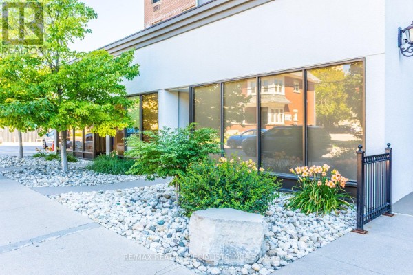 Exterior of building with large windows, landscaping, and white stone ground cover. - 601 - 55 Yarmouth Street, Guelph