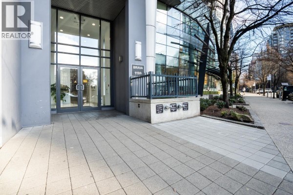 Entrance to the BRAVA 1199 building with a paved walkway and modern glass doors. - 601 1199 Seymour Street, Vancouver