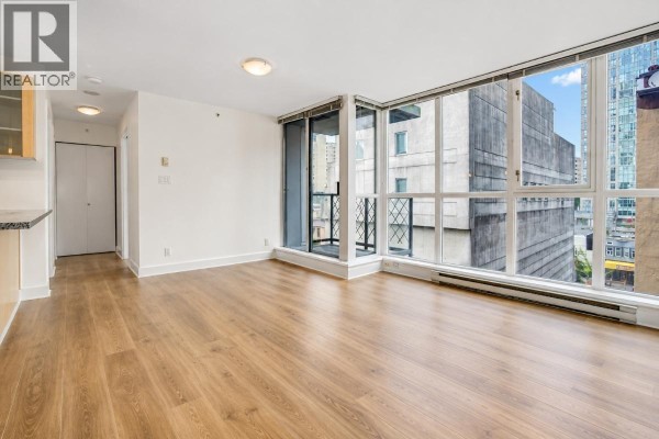 Empty living room with light wood floors, large windows, and a small balcony. - 601 1199 Seymour Street, Vancouver