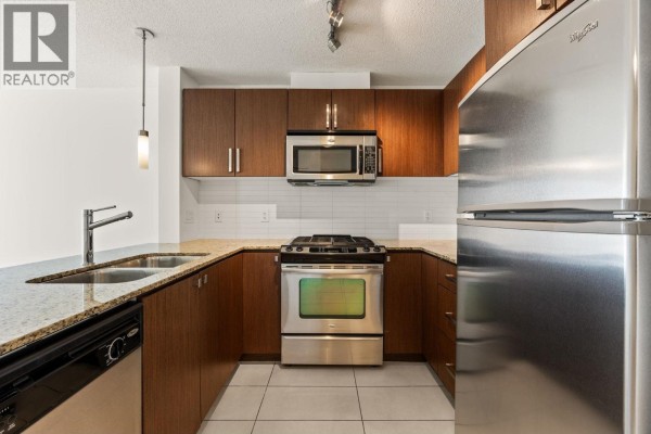 Close-up of a kitchen with stainless steel appliances, dark wood cabinets, and granite countertops. - 601 9868 Cameron Street, Burnaby