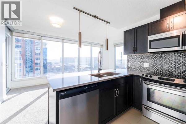 Contemporary kitchen with stainless steel appliances and pendant lighting - 602, 1320 1 Street Se, Calgary