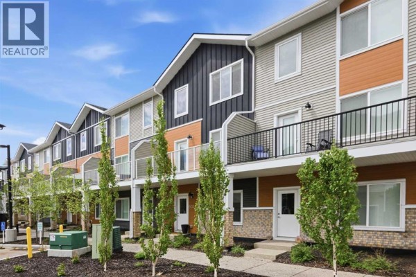 Exterior of a modern townhouse complex with multi-colored siding and garage doors. - 602, 335 Creekside Boulevard Sw, Calgary