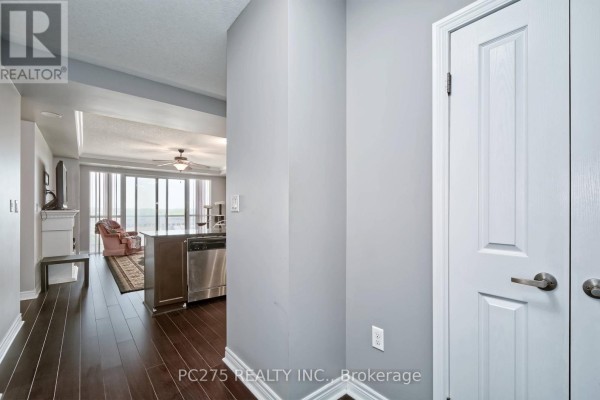 A hallway entrance to an apartment with light gray walls and white doors, leading to a living area. - 602 - 1030 Coronation Drive, London North