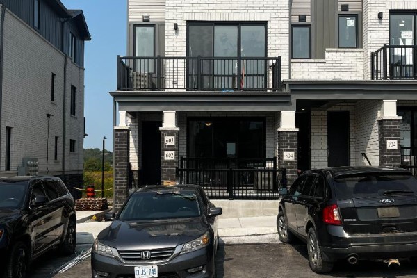 Street view of modern townhouses including units 602, 603, and 604 with parked cars. - 602 - 160 Densmore Road, Cobourg