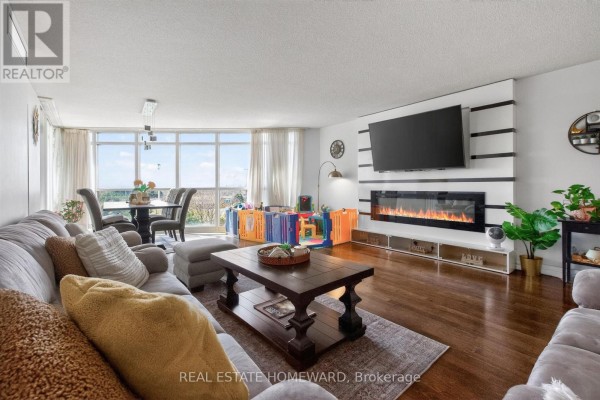 Spacious living and dining area with large windows, dining table, and grey sectional sofa. - 602 - 30 Harrison Garden Boulevard, Toronto