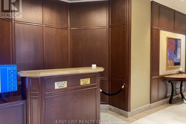 Concierge desk with wood paneling, marble counter, and suite signage. - 602 - 3590 Rivergate Way, Ottawa