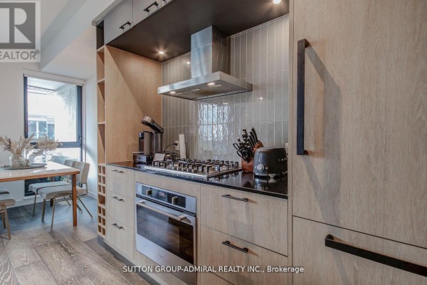 Kitchen with stainless steel appliances, light wood cabinets, grey backsplash, and a gas range. - 602 - 41 Dovercourt Road, Toronto
